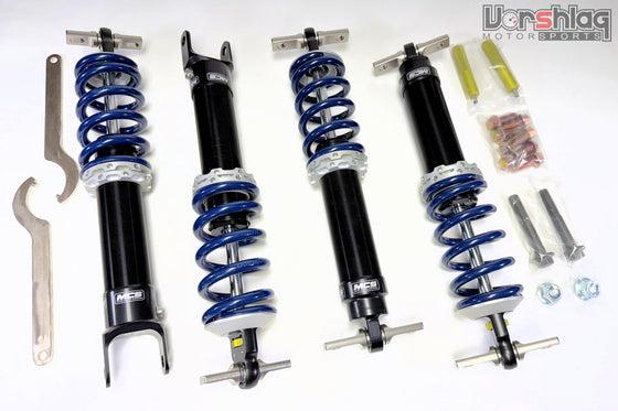 C7 MCS Suspension with mounting hardware, including wrenches, bolts, nuts, and washers, arranged on a white background. Vorshlag Motorsports logo in top right corner